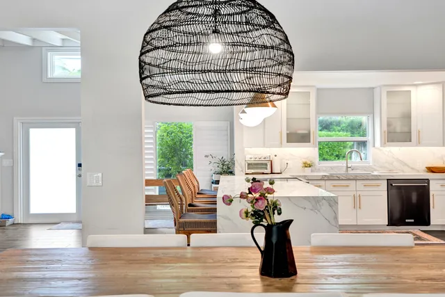 a kitchen with a sink dishwasher a dining table and chairs with wooden floor
