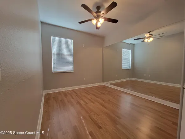 a view of empty room with wooden floor and fan
