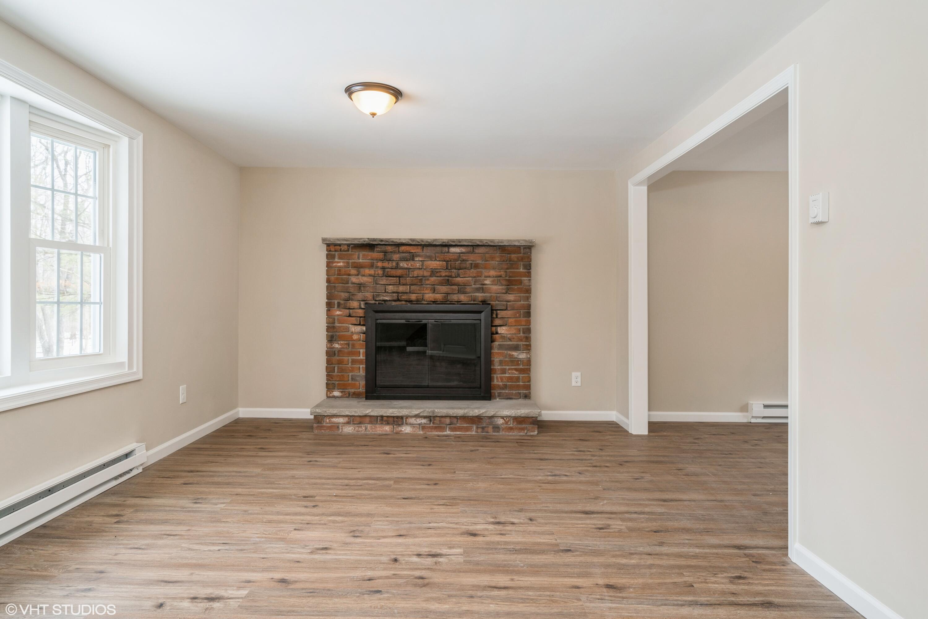 122 Fox Road Dingmans Ferry, PA 18328 - Photo 3 of 15 an empty room with wooden floor a fireplace and windows