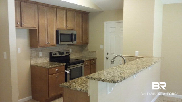 31249 Shambo Road Daphne, AL 36527 - Photo 4 of 7 This compact but functional kitchen has a built in pantry closet, granite tops, and custom subway tile wainscot. Solid wood cabinets and stainless appliances give the kitchen a modern appeal.