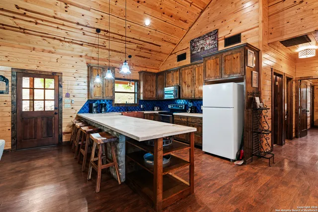 a kitchen with stainless steel appliances granite countertop a refrigerator a stove a sink a dining table and chairs with wooden floor