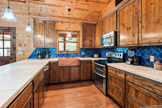 a kitchen with stainless steel appliances granite countertop a sink a stove and a wooden cabinets