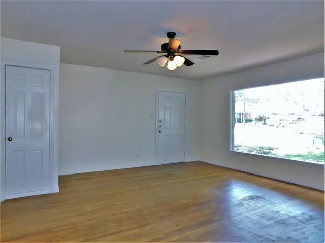 a view of an empty room with wooden floor and a window