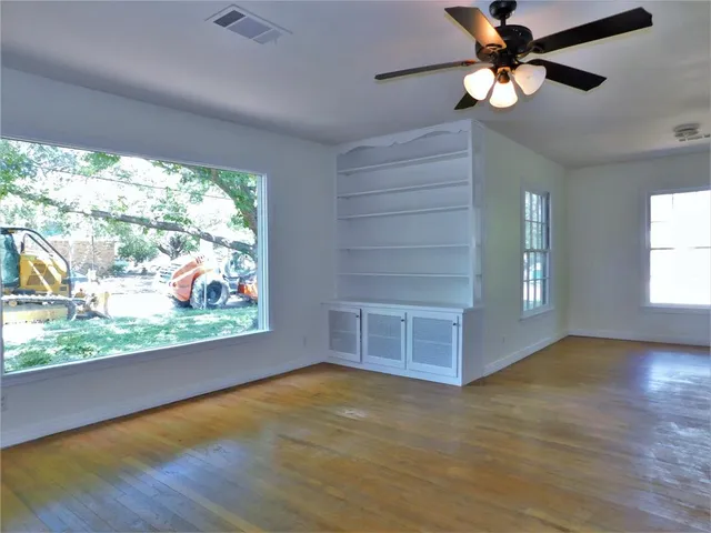 en empty room with windows and ceiling fan