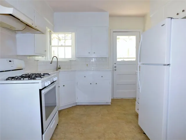 a kitchen with granite countertop a sink stove and refrigerator