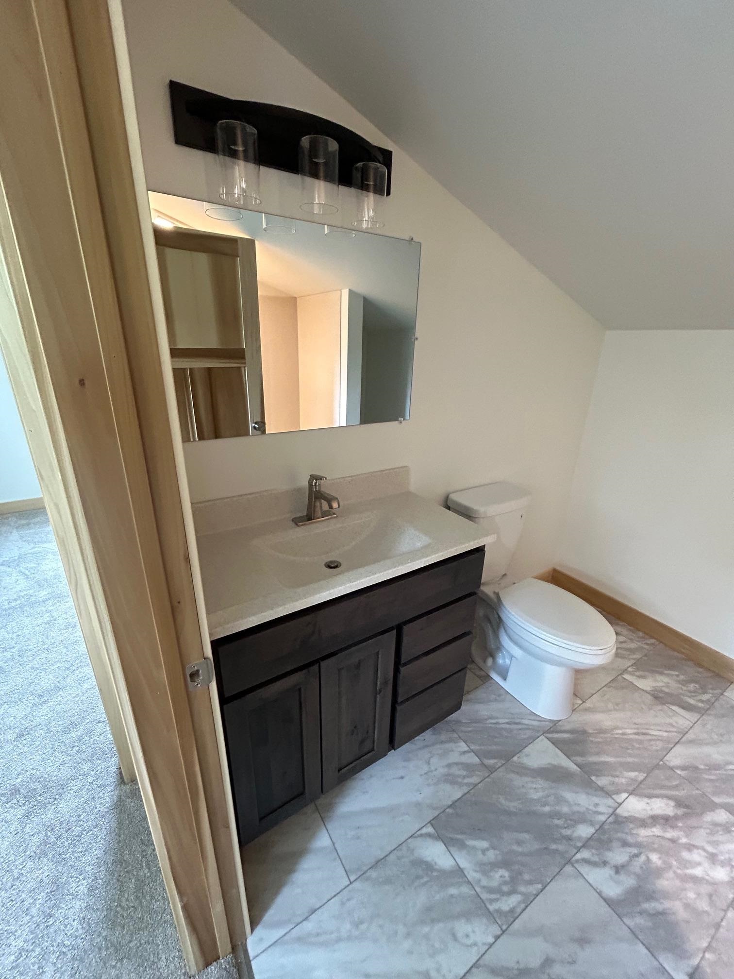 23190 Sawgrass Road Cornucopia, WI 54827 - Photo 22 of 23 Bathroom with vaulted ceiling, vanity, tile patterned flooring, and toilet