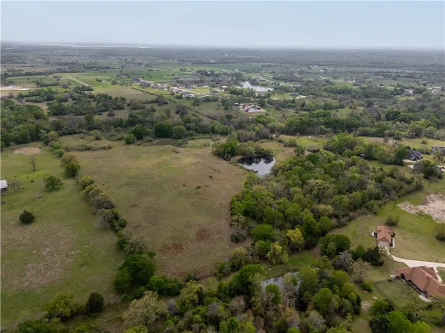 an aerial view of a houses with outdoor space and trees all around