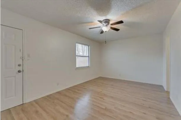 an empty room with a window and a ceiling fan