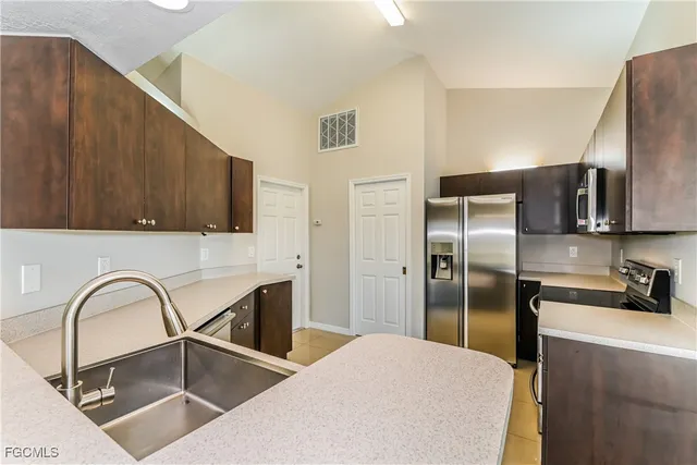 a kitchen with stainless steel appliances kitchen island a refrigerator sink and cabinets
