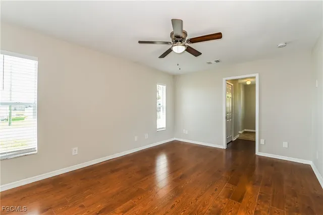 a view of an empty room with wooden floor and a window