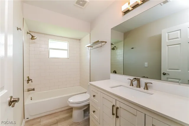 a bathroom with a granite countertop sink a toilet and shower