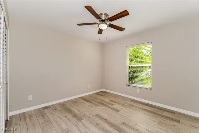 an empty room with ceiling fan and windows