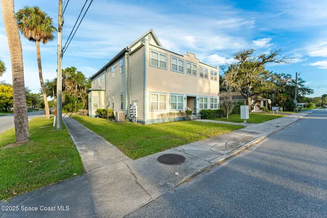 a view of a big house with a big yard and large tree
