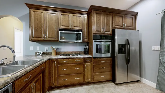 a kitchen with stainless steel appliances granite countertop a refrigerator a stove a sink and cabinets