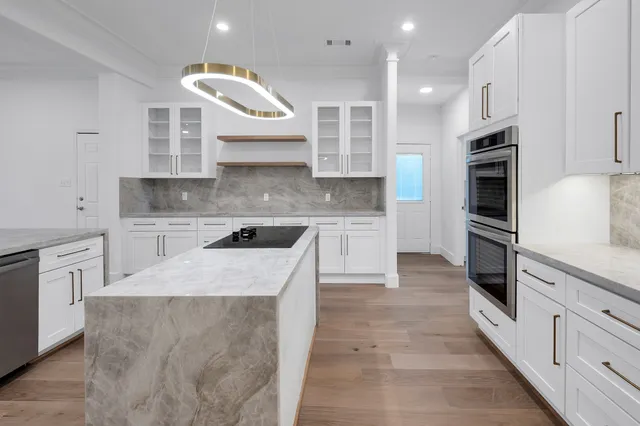 a large kitchen with stainless steel appliances kitchen island a large counter top and wooden cabinets