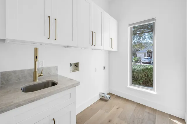 a kitchen with stainless steel appliances granite countertop a sink a window and white cabinets