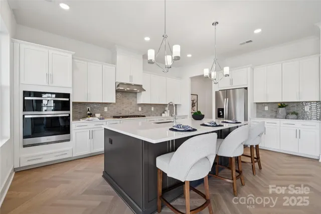 a kitchen with stainless steel appliances kitchen island a table chairs sink and cabinets