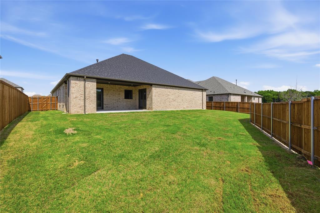 709 Anne Road Van Alstyne, TX 75495 - Photo 28 of 28 Expansive backyard with a manicured lawn, full privacy fencing, and a covered concrete patio