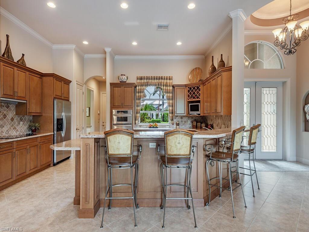 1749 Supreme Court Naples, FL 34110 - Photo 5 of 18 a kitchen with stainless steel appliances kitchen island granite countertop a table and chairs