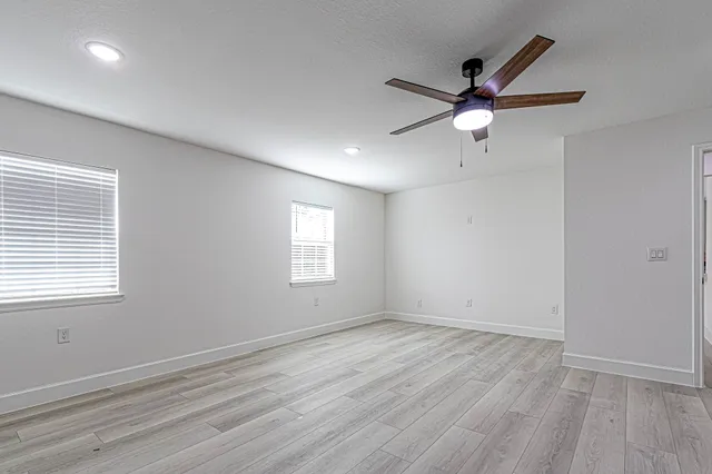 a view of empty room with wooden floor and fan