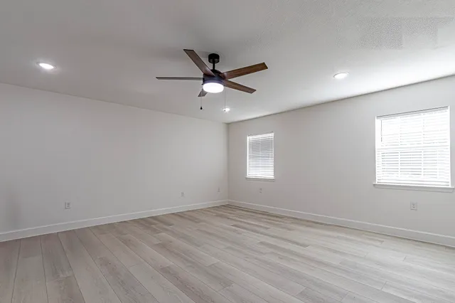 an empty room with wooden floor and windows