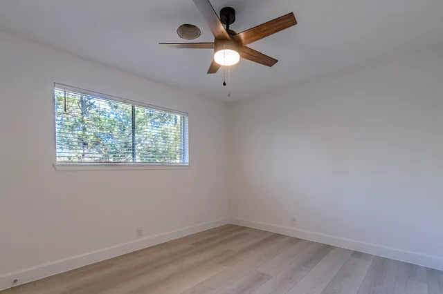 an empty room with a window and a fan