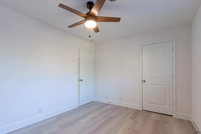 an empty room with a window and a fan