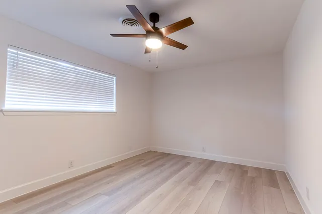 an empty room with a window and a ceiling fan