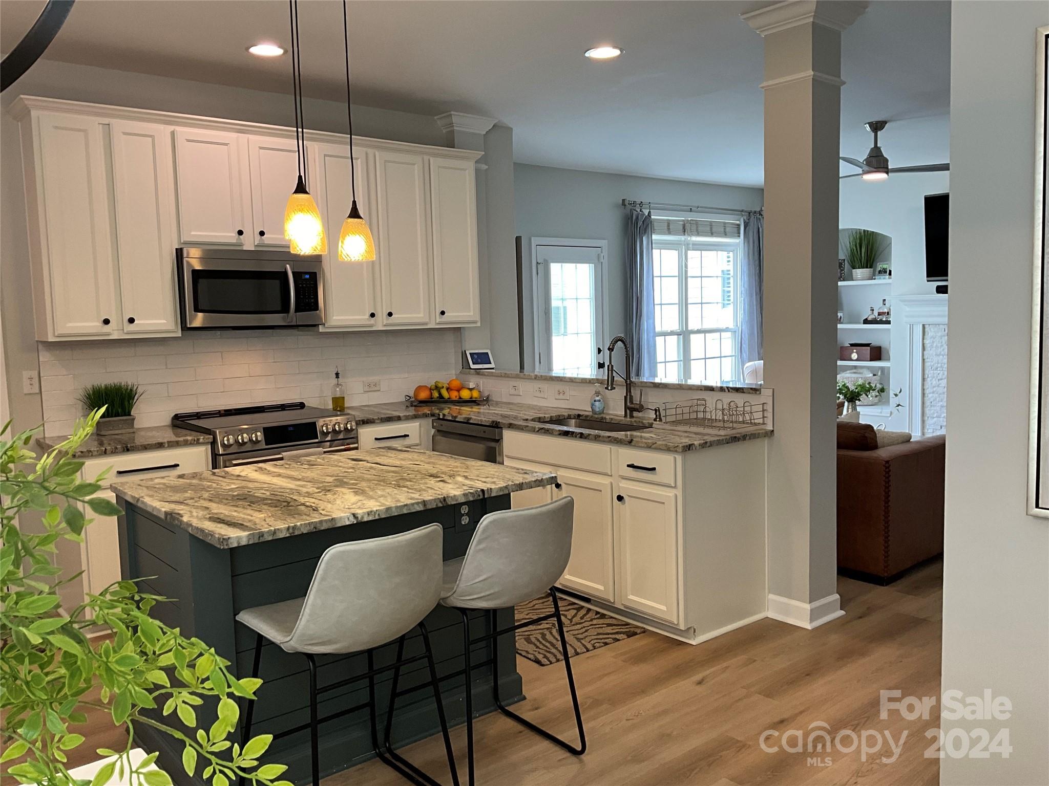 8126 Evanston Falls Road Huntersville, NC 28078 - Photo 19 of 42 a kitchen with stainless steel appliances granite countertop a stove a sink a microwave a refrigerator and white cabinets with wooden floor