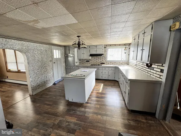 a large kitchen with kitchen island a stove a sink dishwasher and white cabinets with wooden floor