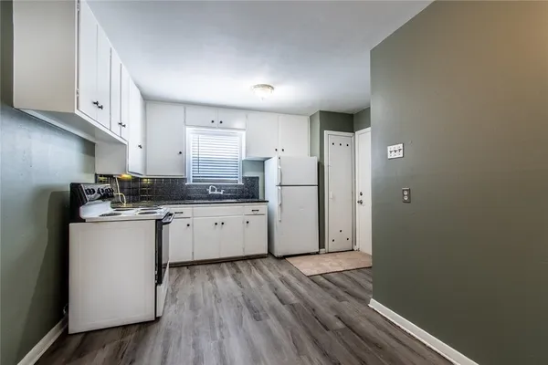 a kitchen with a refrigerator and white cabinets