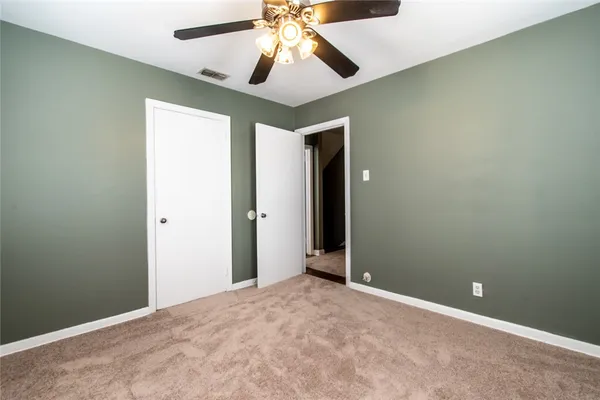 an empty room with chandelier fan and a ceiling fan