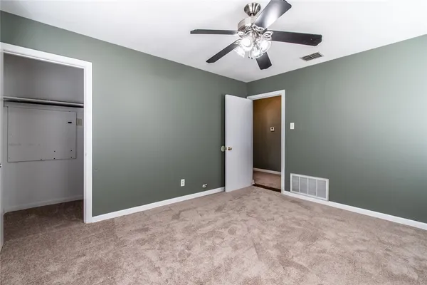 an empty room with closet and a ceiling fan
