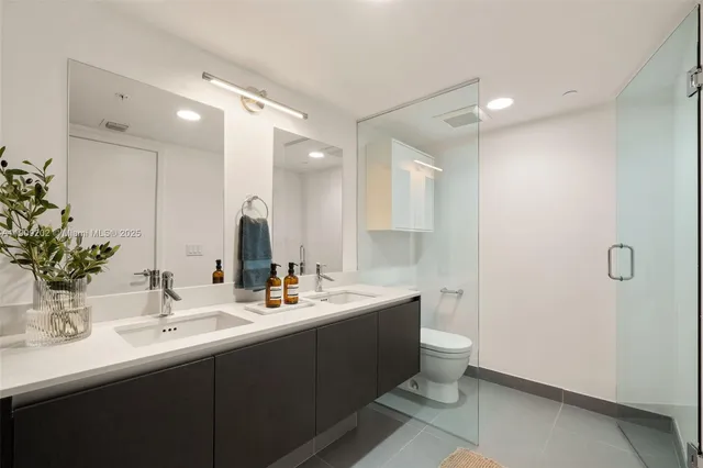 a bathroom with a double vanity sink toilet and a mirror