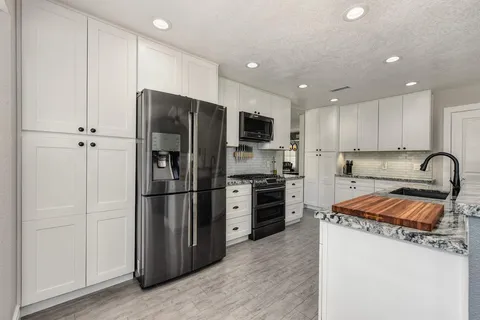 a kitchen with stainless steel appliances granite countertop a refrigerator stove microwave and sink