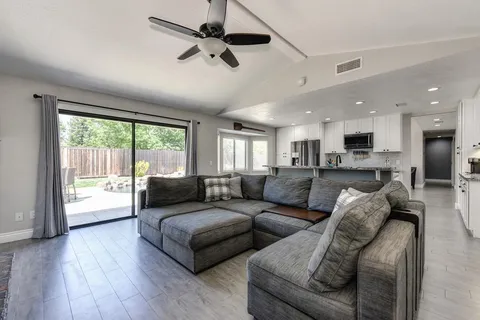 a living room with furniture and a large window with kitchen view