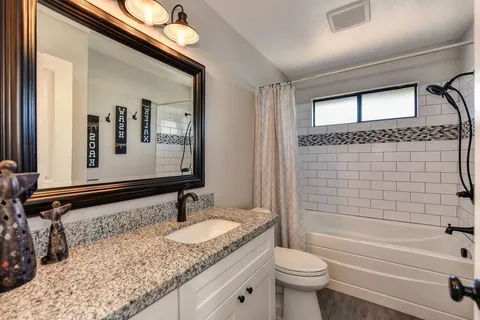 a bathroom with a granite countertop sink mirror toilet and bathtub