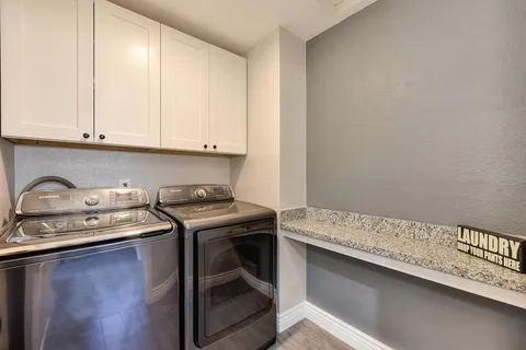 a utility room with granite countertop cabinets washer and dryer