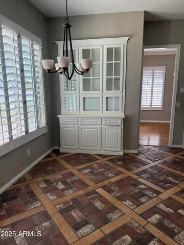 an empty room with chandelier fan and windows