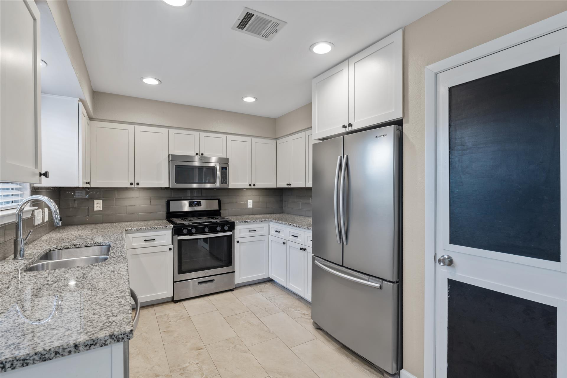 1710 Persimmon Road Cedar Park, TX 78613 - Photo 13 of 33 A well-appointed kitchen showcasing elegant cabinetry, granite countertops, and pantry with a chalkboard door.