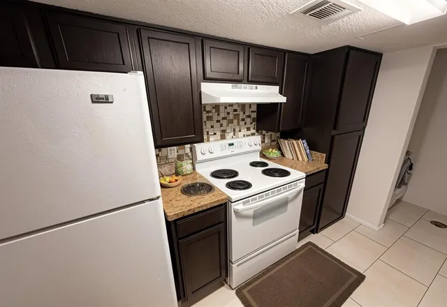 a white refrigerator freezer and a stove sitting inside of a kitchen