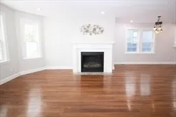 an empty room with wooden floor fireplace and windows