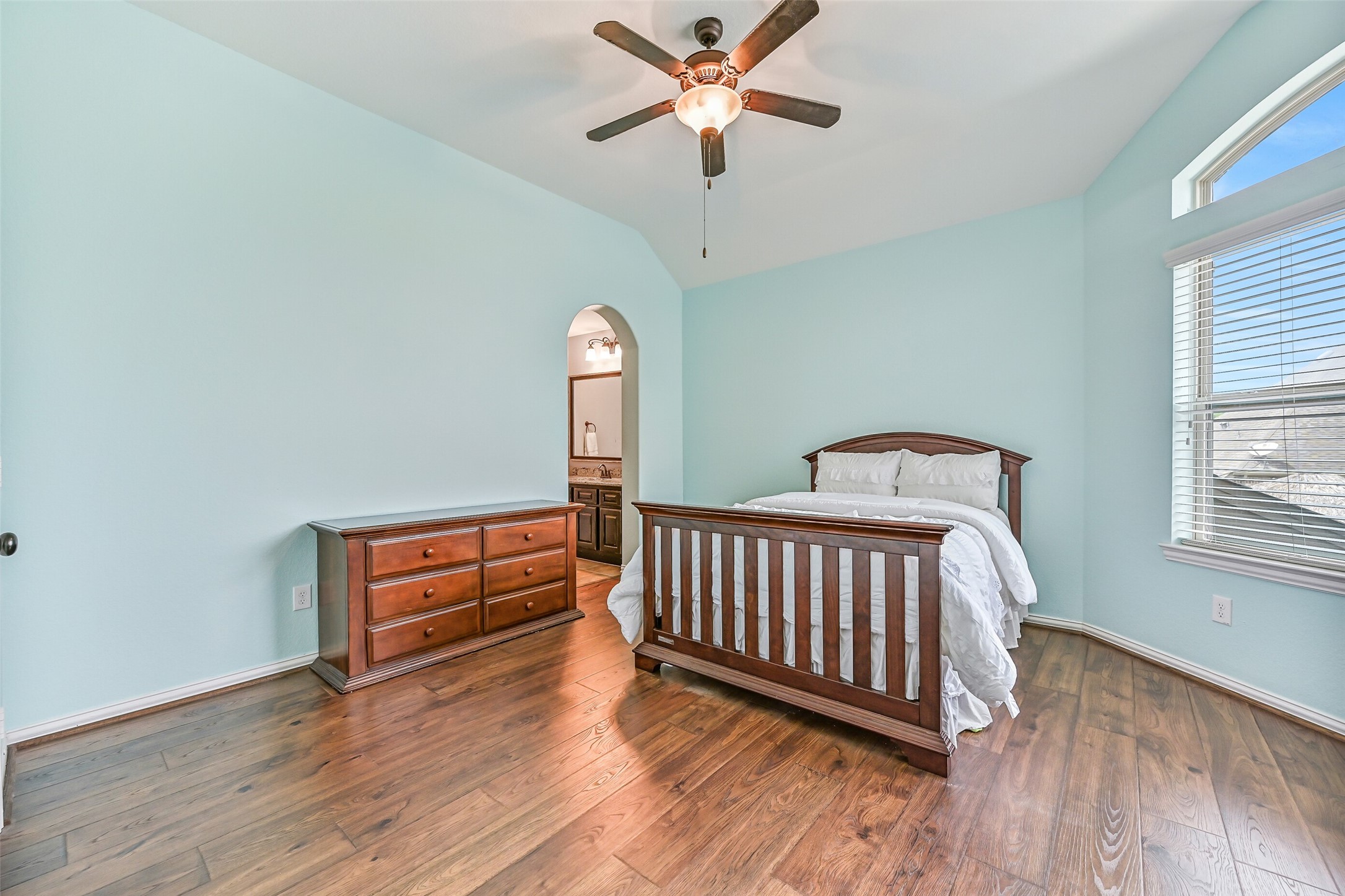 1008 Point Isabel Lane Friendswood, TX 77546 - Photo 42 of 50 Another well sized secondary bedroom offers wood look flooring, soft natural light from a front facing arched window, and a similar color palette, creating a comfortable and versatile space for guests or family.
