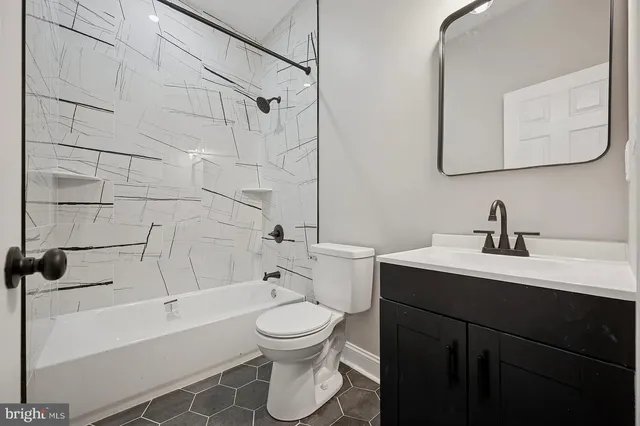 a bathroom with a bathtub shower sink vanity mirror and toilet
