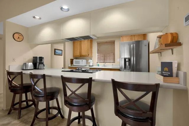 a kitchen with stainless steel appliances kitchen island granite countertop a dining table chairs and a refrigerator