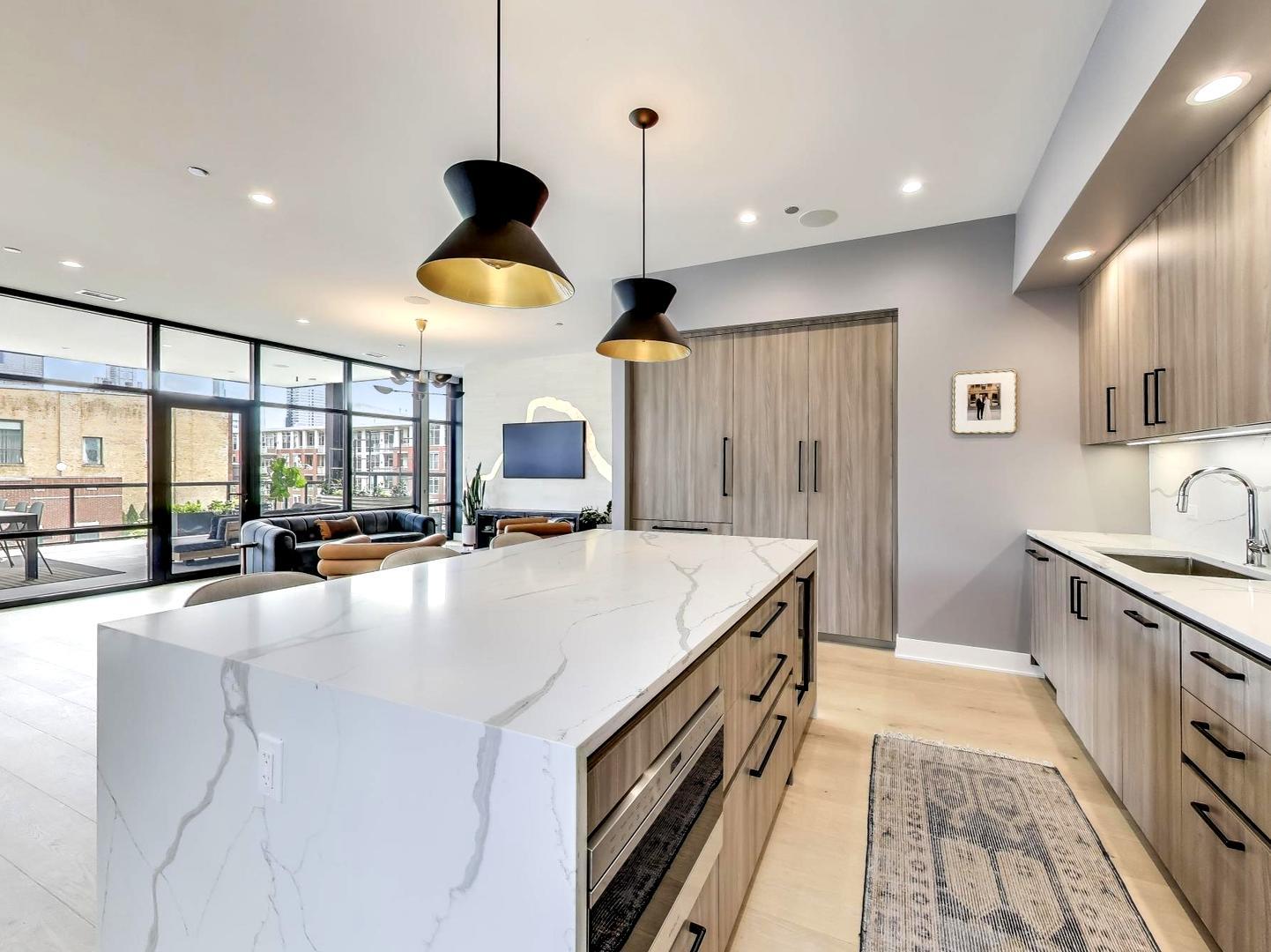 6 North Carpenter Street, Unit 5B Chicago, IL 60607 - Photo 7 of 40 a large kitchen with stainless steel appliances a large counter top a stove a chimney a sink and a large window