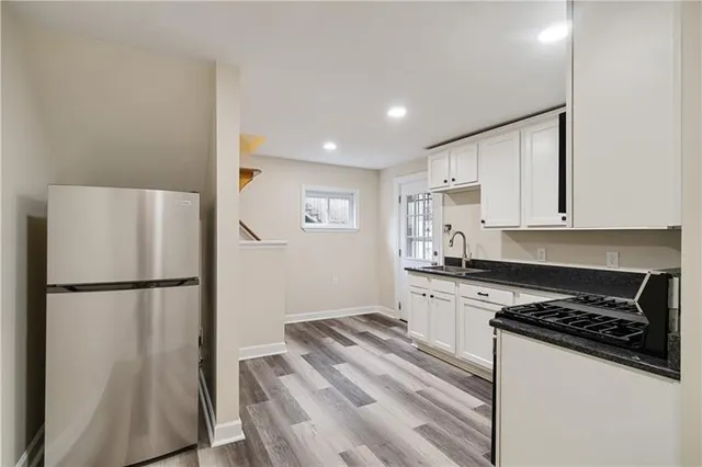 a kitchen with a refrigerator a stove and white cabinets