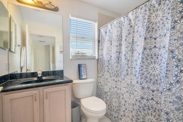 a bathroom with a granite countertop sink a toilet and a mirror