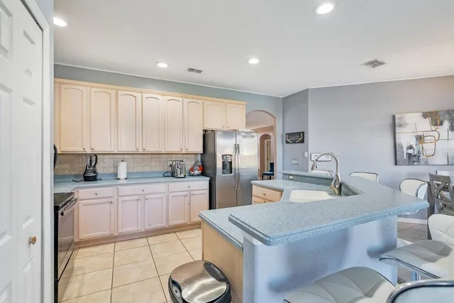 a kitchen with a sink a stove a refrigerator cabinets and a dining table