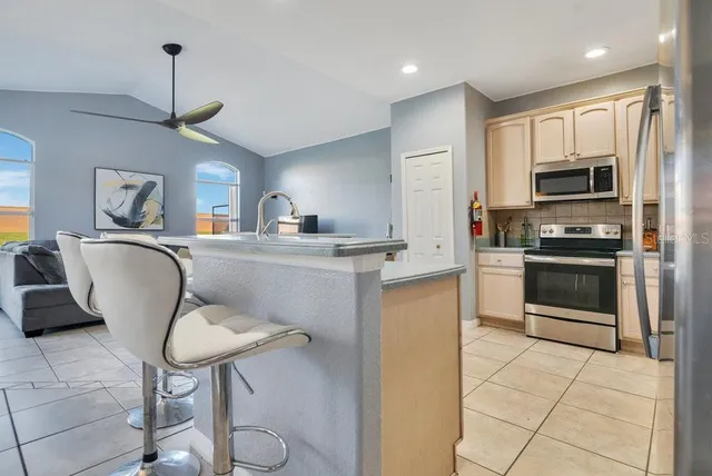 a kitchen with stainless steel appliances a stove a sink a microwave a dining table and chairs